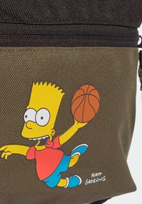 Zaino khaki con un personaggio dei cartoni animati, un ragazzo dalla pelle gialla con una maglietta rossa e pantaloni blu, che tiene in mano un pallone da basket, tessuto testurizzato.
