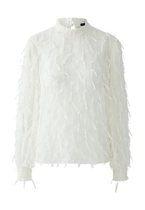 Weiße Bluse mit langen Ärmeln, hohem Kragen und gerafften Bündchen. Besteht aus strukturiertem Stoff mit mehreren zarten, ausgefransten Details über das gesamte Kleidungsstück verteilt.