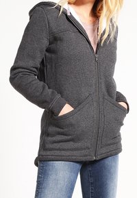 Grå fleecezip-hoodie med huva, framfickor och texturerad tyg. Har en mjuk insida och ribbade ärmslut.