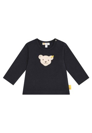 Marineblaues Langarmshirt mit Rundhalsausschnitt, das auf der Vorderseite ein weiches cremefarbenes Bärenkopf-Applikation und ein gelbes Etikett an der Seite aufweist.