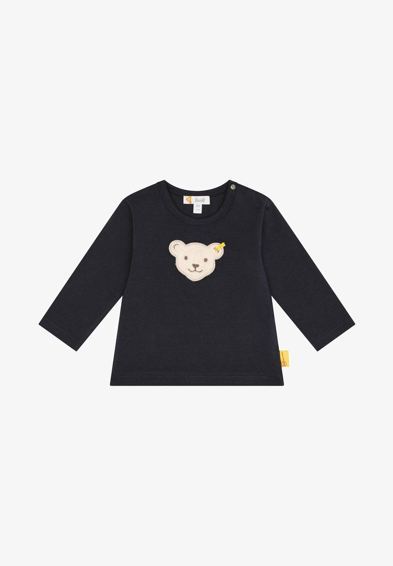 Marineblaues Langarmshirt mit Rundhalsausschnitt, das auf der Vorderseite ein weiches cremefarbenes Bärenkopf-Applikation und ein gelbes Etikett an der Seite aufweist.