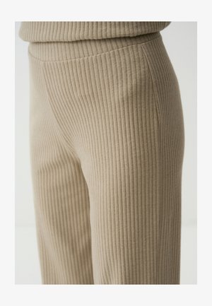 Beige Rippenstoffhosen mit leichtem Glanz, die ein elegantes Design und eine glatte Textur aufweisen und bis zu einem geraden Bein reichen.