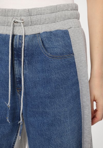 Jasnoszara talia dresów z sznurkiem, w połączeniu z niebieskim materiałem dżinsowym. Posiada kieszenie i kontrastujące szare boki. Miękka faktura.