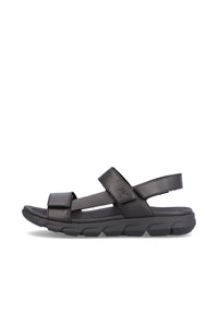 Sandale noire avec des sangles réglables en Velcro, une semelle intérieure rembourrée et une semelle en caoutchouc texturé conçue pour le confort et la stabilité.