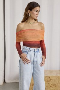 Off-shoulder topp med gradientnyanser fra oransje til rød, med rynket stoff. Brukt med lys blå høyt midje jeans.