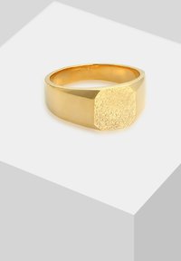 Guldring med en geometrisk, tekstureret oktagonal top og en glat ring, der fremhæver en poleret finish og en karakteristisk form.