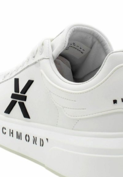 Białe trampki z teksturowaną powierzchnią, wyraźnym czarnym logo i akcentami oraz masywną białą podeszwą z napisem "RICHMOND" po boku.
