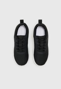Black athletic shoes made of mesh fabric with a textured surface, lace-up design, and a white rubber sole. Two pull tabs on the heel.