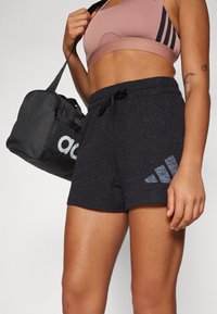 Calções atléticos pretos feitos de um tecido texturizado, com um cós elástico, cordão de ajuste e um logótipo cinza da adidas impresso numa perna.