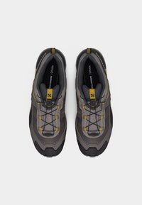 Ζευγάρι γκρι και κίτρινων παπουτσιών trail running Salomon με σύστημα γρήγορου κορδονιού, από πάνω σε λευκό φόντο.