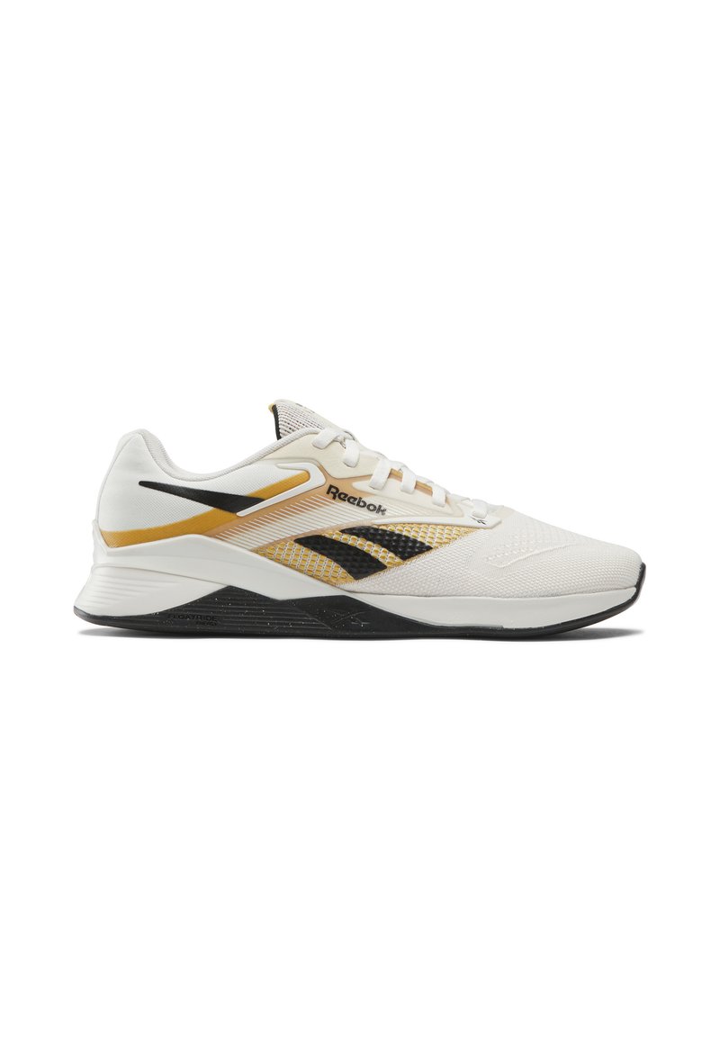 Zapatilla deportiva blanca con detalles en negro y dorado. Presenta una parte superior de malla, detalles texturizados y una suela negra texturizada para un mejor agarre.