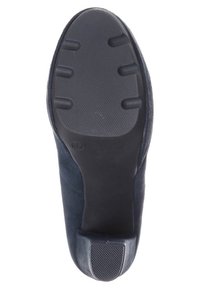 Navy modré semišové podrážky s texturovanou černou gumovou základnou. Obsahuje kulaté vzory na běhounu a mírný podpatek pro lepší přilnavost a pohodlí.