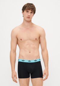 Mustat boxerit sinisellä vyötärönauhoilla, jossa on toistuva logokuviomerkintä. Kangas näyttää sileältä ja on muotoilultaan tuntumaltaan istuva.