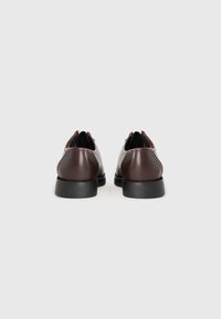Scarpe in pelle marrone con una finitura liscia, punta tonda e suole in gomma nera. Presentano cuciture minime e un tacco discreto.