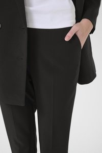 Sort dressbukse med en strukturert blazer og rette bukser, kombinert med en tettsittende hvit tanktop, glatt tekstur.