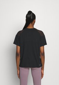 Maglietta sportiva nera con maniche corte e pannelli in rete sulle spalle. Design semplice, vestibilità rilassata. Solo vista posteriore.