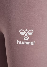 Light purple athletic leggings featuring a textured finish and a white "hummel" logo with a stylized bee design on the side.