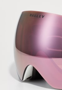Oakley skibriller med en buet rosa linse, hvite detaljer og svarte kontraster. Har et strømlinjeformet design med en glatt, reflekterende overflate.