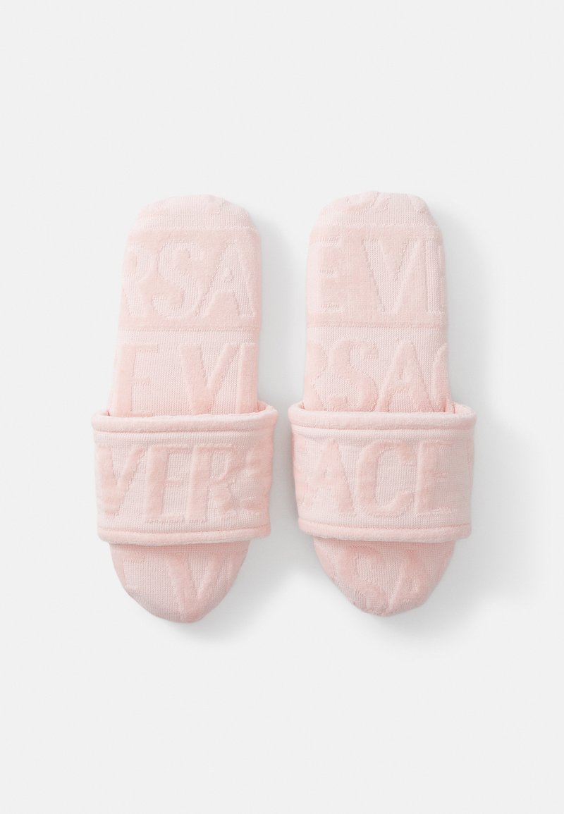 Pantofole in peluche rosa con un design testurizzato e lettering impresso. Materiale morbido con una fascia imbottita per il comfort.