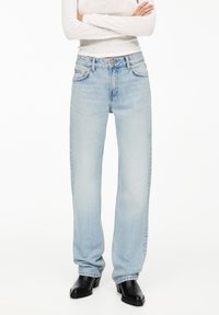 Ljusblå raka jeans med fem fickor, knappstängning och subtila stickningsdetaljer. Bärs med svarta klackstövlar.