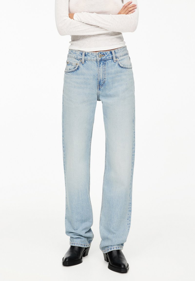 Ljusblå raka jeans med fem fickor, knappstängning och subtila stickningsdetaljer. Bärs med svarta klackstövlar.