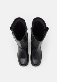 Svarta knähöga stövlar i läder med slät yta, rundade tår, sidodragkedjor och en elegant design. Insidan är fodrad med mjukt tyg.