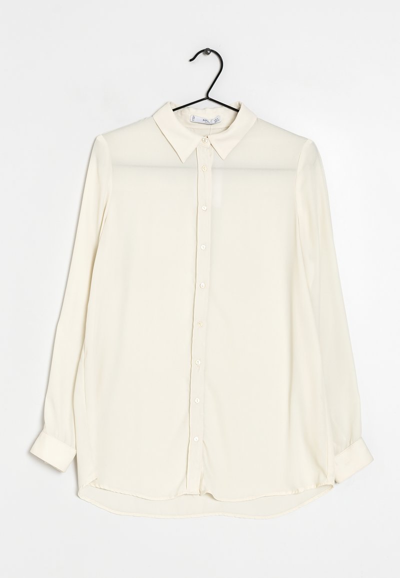 Chemise longue à manches longues beige clair avec col classique, fermeture à boutons et ourlet légèrement incurvé. Fabriquée en tissu lisse et léger.