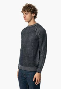 Maglione a righe navy con collo a giro, texture a coste e design aderente. Abbinato a jeans di denim scuro.