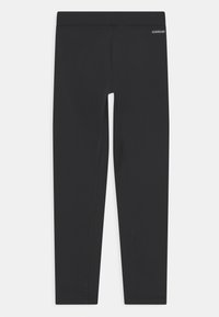 Leggings noirs fabriqués en tissu extensible, avec une taille élastique et un branding subtil sur le côté. Texture lisse et sans motifs visibles.