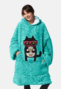 Türkise Übergröße-Hoodie mit einem Katzenmotiv, die pinke Brille trägt und eine Kaffeetasse hält, akzentuiert durch wirbelnde dekorative Muster.