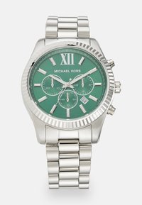 Silver metal chronograph watch with green face, large Roman numeral XII, three sub-dials, and a textured bezel. Adjustable link bracelet.