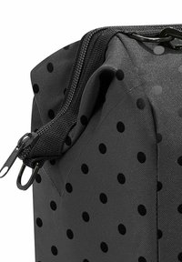 Black fabric bag with prominent black polka dots, featuring a sturdy zipper and textured surface, side view highlighting construction details.