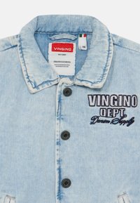 Svijetloplavi traper jakna s ovratnikom, dva crna gumba i izvezenim tekstom "Vingino Dept. Denim Supply." Ima istrošeni izgled.