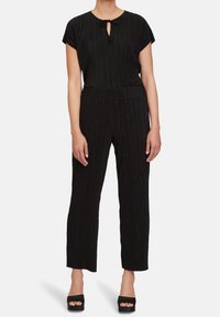 Černý overal s vertikálními pruhy, krátkými rukávy a výstřihem s klíčovou dírkou. Má volný střih a zúžené nohavice, vyrobený z lehké látky.