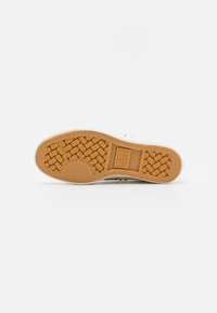 Suela de zapatilla de goma en color gum con un patrón de espiga texturizado y un corte circular, que presenta la marca "ALL STAR".