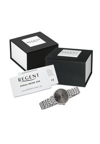 Montre Regent avec un cadran rond noir, bracelet en acier inoxydable argenté présentant un design texturé, accompagnée de deux boîtes noires et d'une carte de garantie.