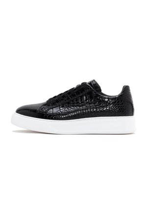 Baskets basses noires à texture crocodile, lacets noirs et semelle épaisse en caoutchouc blanc, présentées en profil latéral face à gauche.