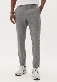 Pantaloni a quadri grigi con una vestibilità slim, caratterizzati da un fondopiano, tasche laterali e cuciture decorative. Indossati con sneakers grigie.