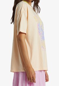 Licht perzik oversized t-shirt met een levendige grafische print. Korte mouwen, ronde halslijn en zachte katoenen textuur.