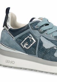 Baskets en denim bleu avec des accents en daim et en cuir lisse, détails en métal argenté, surface texturée et semelle en caoutchouc blanc.