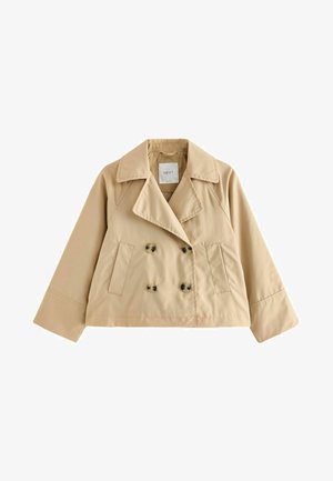 Beige színű, rövidített trench kabát, dupla soros gombolással, nagy gallérral és két oldalsó zsebbel. Simább, könnyű anyagból készült.