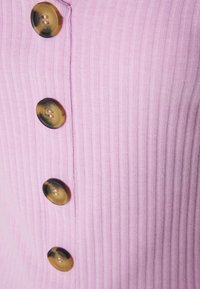 Růžová žebrovaná látka s vertikálními pruhy, s pěti velkými hnědými a béžovými knoflíky podél středu. Hladká textura.
