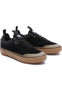 Paire de baskets Vans noires avec semelles en caoutchouc naturel, embouts renforcés et design à lacets, présentées sur un fond blanc.