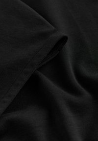 Mustast puuvillast kangas, millel on sile tekstuur, mis langeb pehmelt ja näitab peeneid voldikesi ja servi. Omaduseks on mati viimistlusega pind ilma mustriteta.