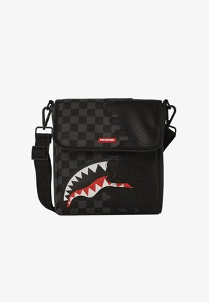 Bolso mensajero negro con patrón de cuadros, que presenta un diseño de tiburón en rojo y blanco. El material es texturizado, cuenta con cierre de solapa y correa ajustable.