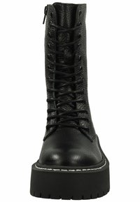 Botas de combate negras con cordones, con un upper de cuero texturizado, suela de goma gruesa y detalle de costura blanca a lo largo del borde de la suela.