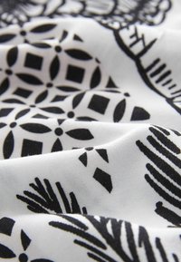 Țesătură alb-negru cu modele florale și geometrice intricate, având o textură netedă și o cădere moale.