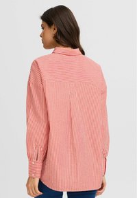 Red and white striped shirt with a collared neckline, long sleeves, and buttoned cuffs; features a back yoke and relaxed fit.