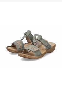 Grüne Wildledersandalen mit offener Zehenpartie, versehen mit Kreuzriemen, dekorativer Naht und einer gepolsterten Innensohle auf einer braunen Gummisohle.