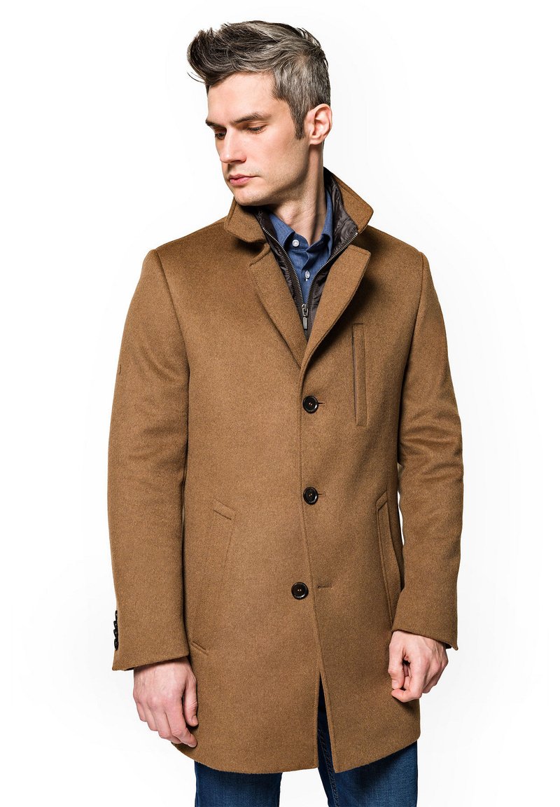 Brązowy płaszcz wełniany z kołnierzem z ząbkami, zapinany na jeden guzik, z bocznymi kieszeniami, noszony na niebieskiej koszuli.
